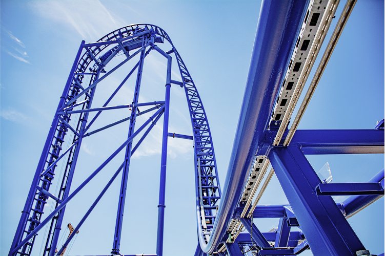 Blue roller coaster track under construction with daylight sky background.