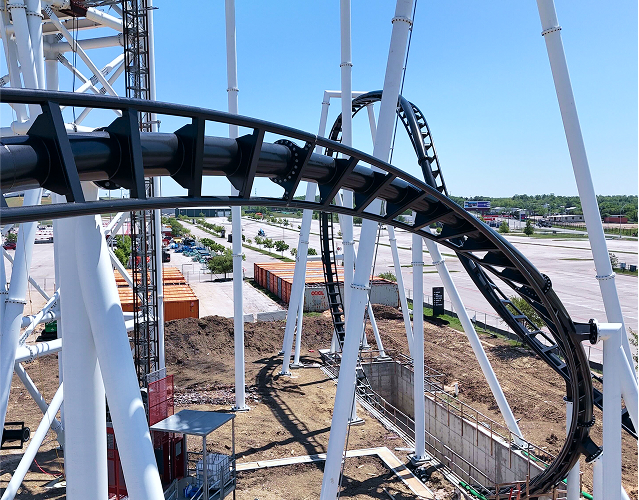 An overhead view of a roller coaster track during construction. The steel structure and surrounding dirt hint at the exciting ride in progress.